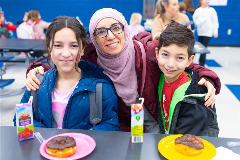 Creekside Elementary students eat donuts with a grown-up